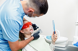 Dentist using shade scale while patient looks in mirror