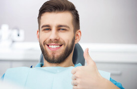 Man in dentist’s chair giving thumbs up