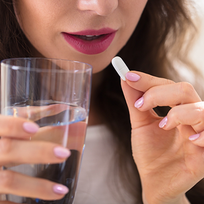 Woman holding pill and glass of water