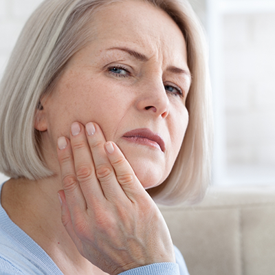 Senior woman rubbing jaw in pain