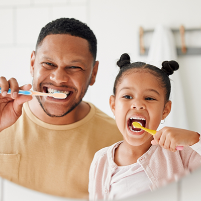 Father and daughter brushing teeth together