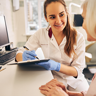 Dental team member entering information into tablet while talking to patient