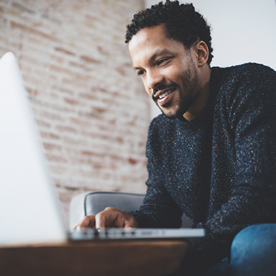 Man sitting on couch and typing on laptop
