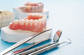 Model of dentures next to dental tools